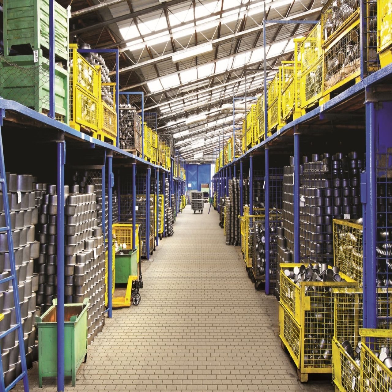 Free A spacious warehouse aisle lined with metal containers stored on blue and yellow shelves, showcasing industrial storage solutions. Stock Photo